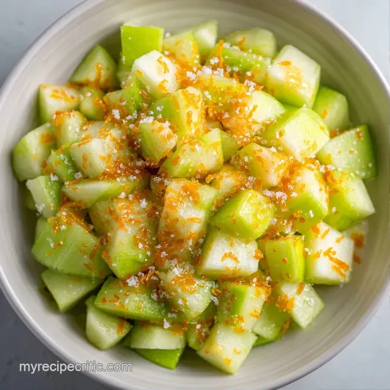 A white marble platter with neatly stacked cubes of pale green apple and ivory cheese garnished with a sprig of mint.
